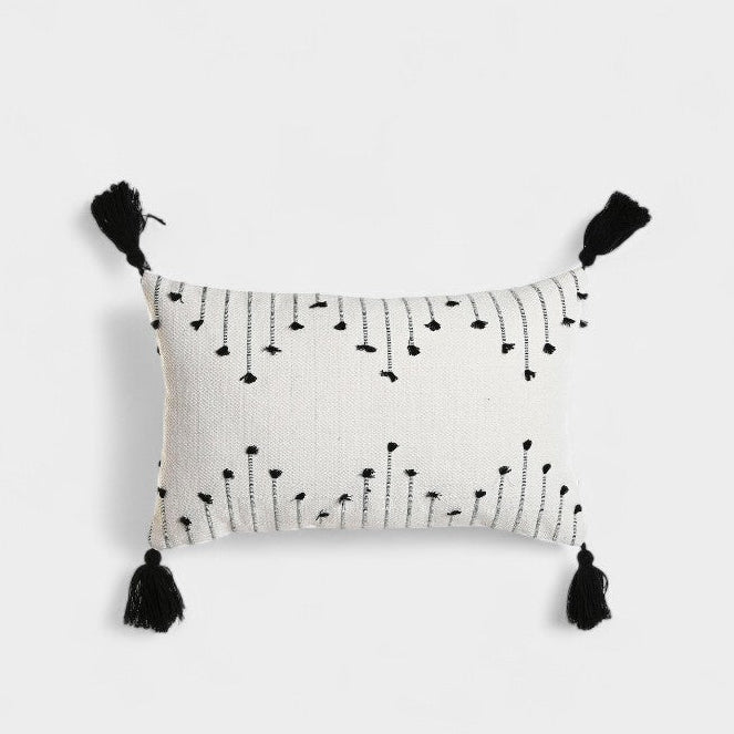 Coussin blanc a broderies noires et pompoms
